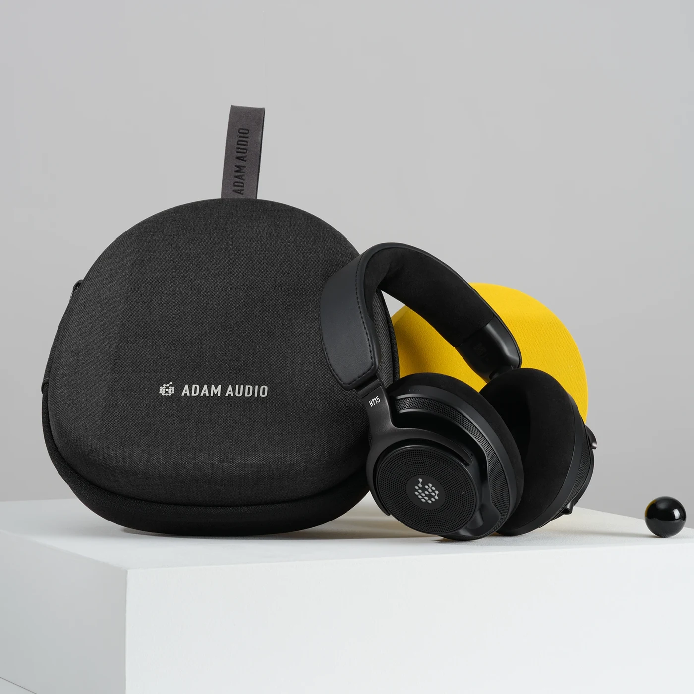 ADAM Audio H715 Reference headphones beside their closed black travel case