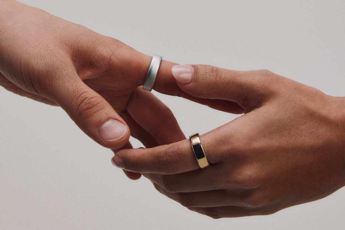 Two hands wearing silver and gold Oura Ring 5 smart rings